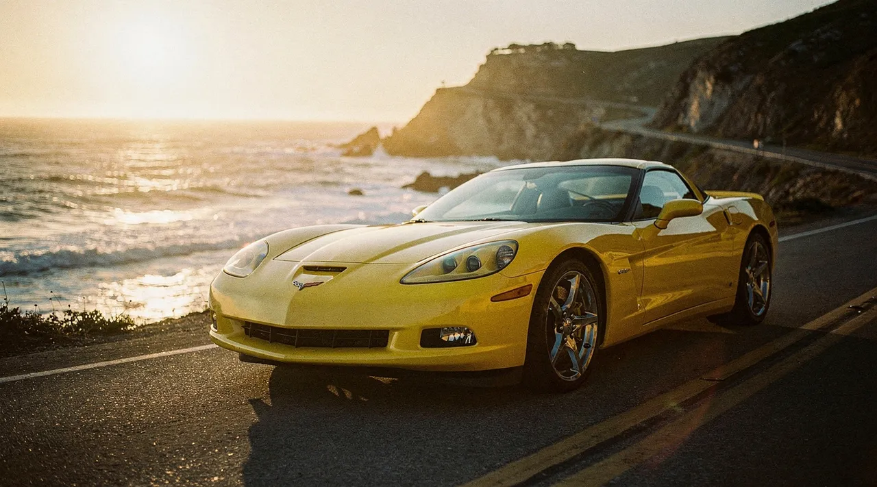 Chevrolet Corvette C6 jaune sur route côtière au coucher du soleil
