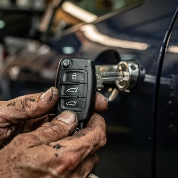 Main insérant une clé Volkswagen dans la serrure d'une portière, atelier en arrière-plan