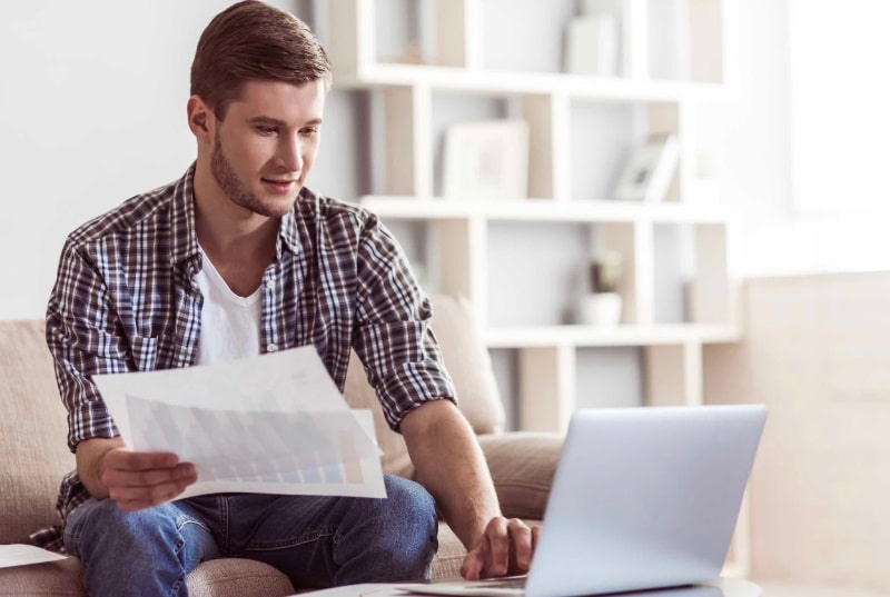 Homme sur un ordinateur avec des documents