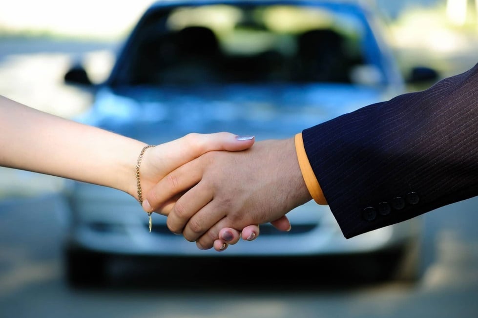 Poignée de main devant une voiture