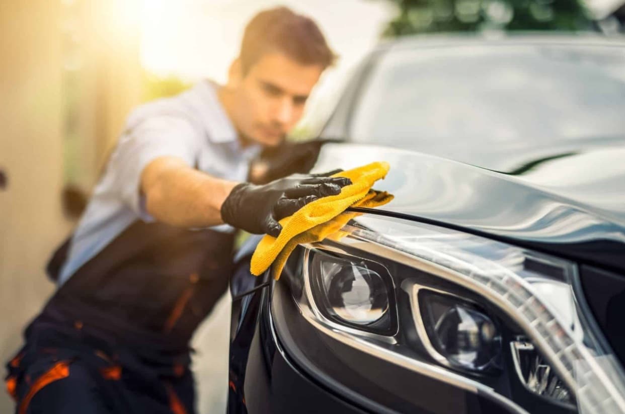 Homme nettoi la carrosserie d'une voiture